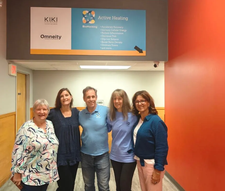 Sargent Goodchild with a group of smiling visitors under the Active Healing BioHacking sign at the Danvers center